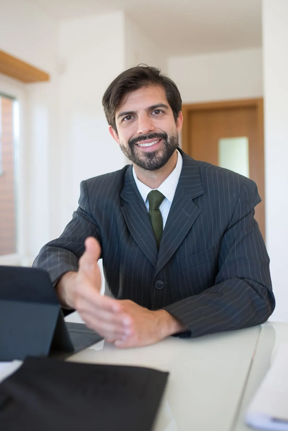 Corretor parceiro da iaRe sorrindo, com tablet na mesa, pronto para atender.